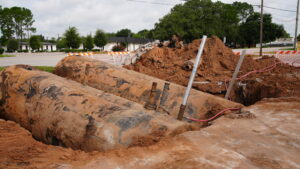 An excavator lifting a rusted underground storage tank out of the ground during a UST removal project in Richmond, Texas