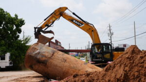 An excavator lifting a rusted underground storage tank out of the ground during a UST removal project in Richmond, Texas